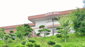 介護施設の建物外観。緑に囲まれた低層建築物の正面全景